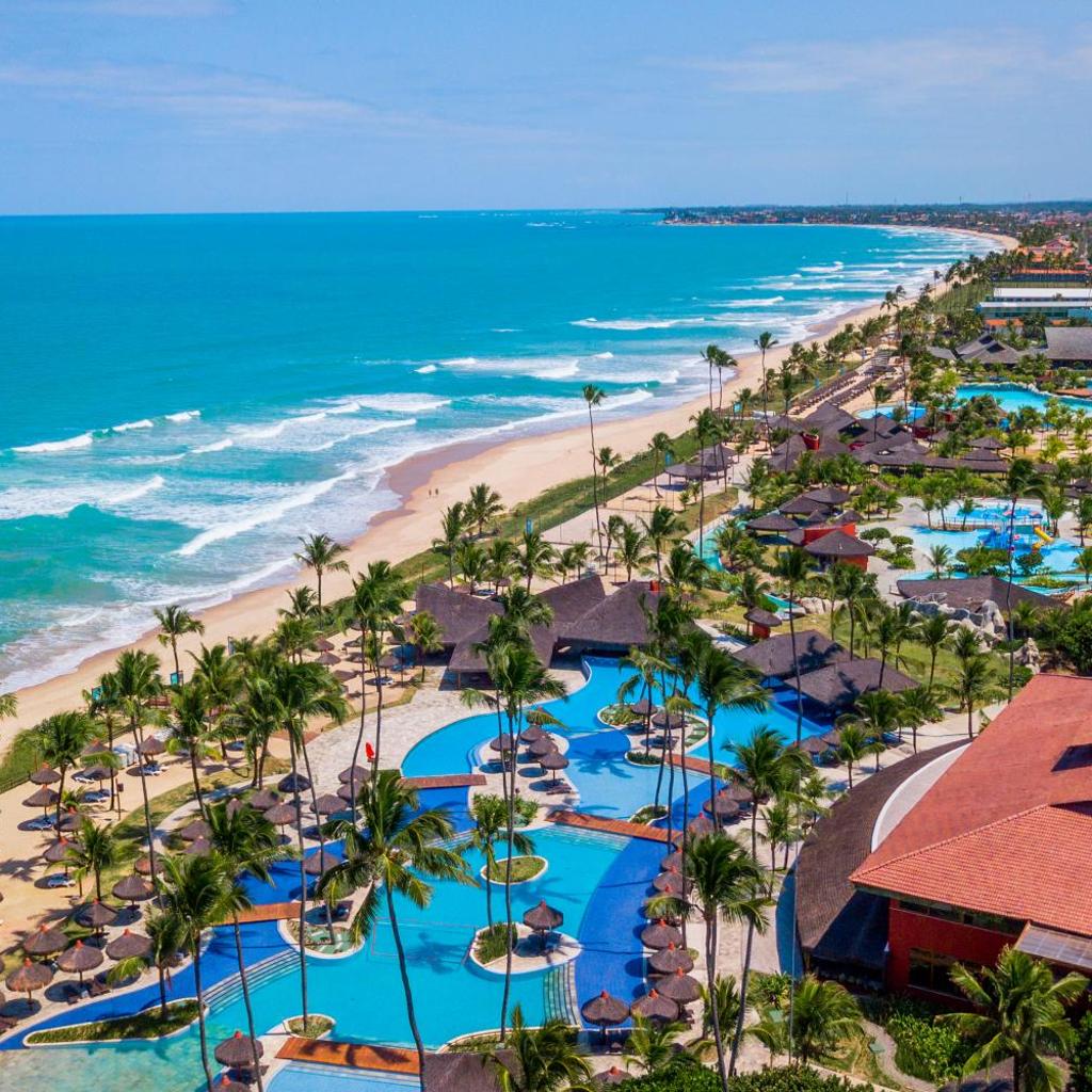 Vista aérea do resort Enotel Porto de Galinhas All Inclusive com piscinas, palmeiras e a costa do oceano.