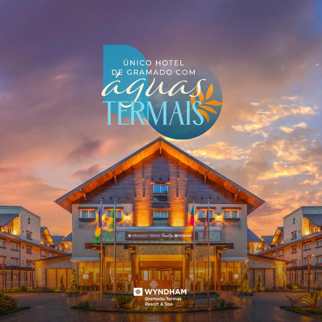 Wyndham Gramado Termas Resort & Spa com bandeiras e uma placa destacando suas águas termais exclusivas ao pôr do sol.